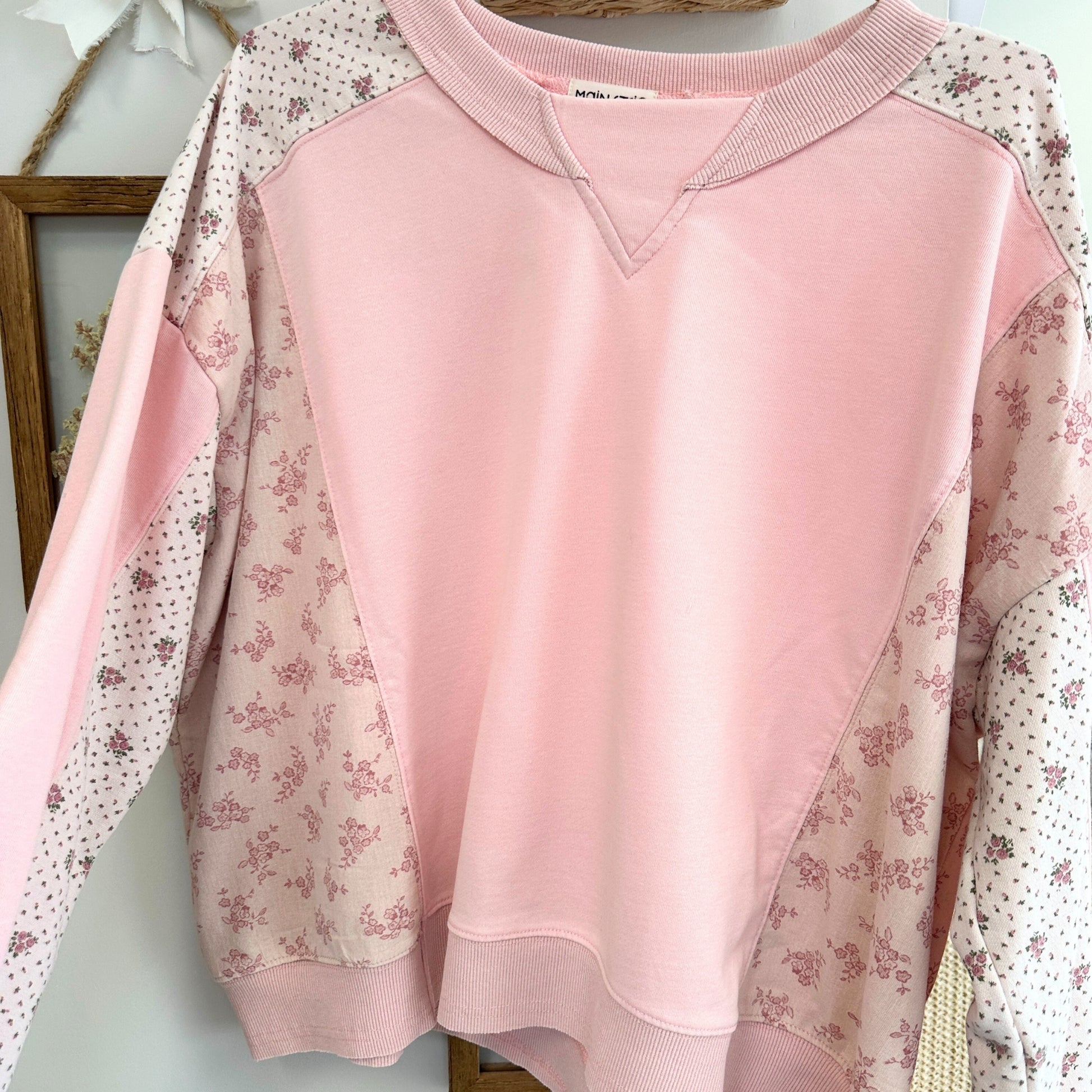 Pink sweatshirt with floral sleeves on a light background