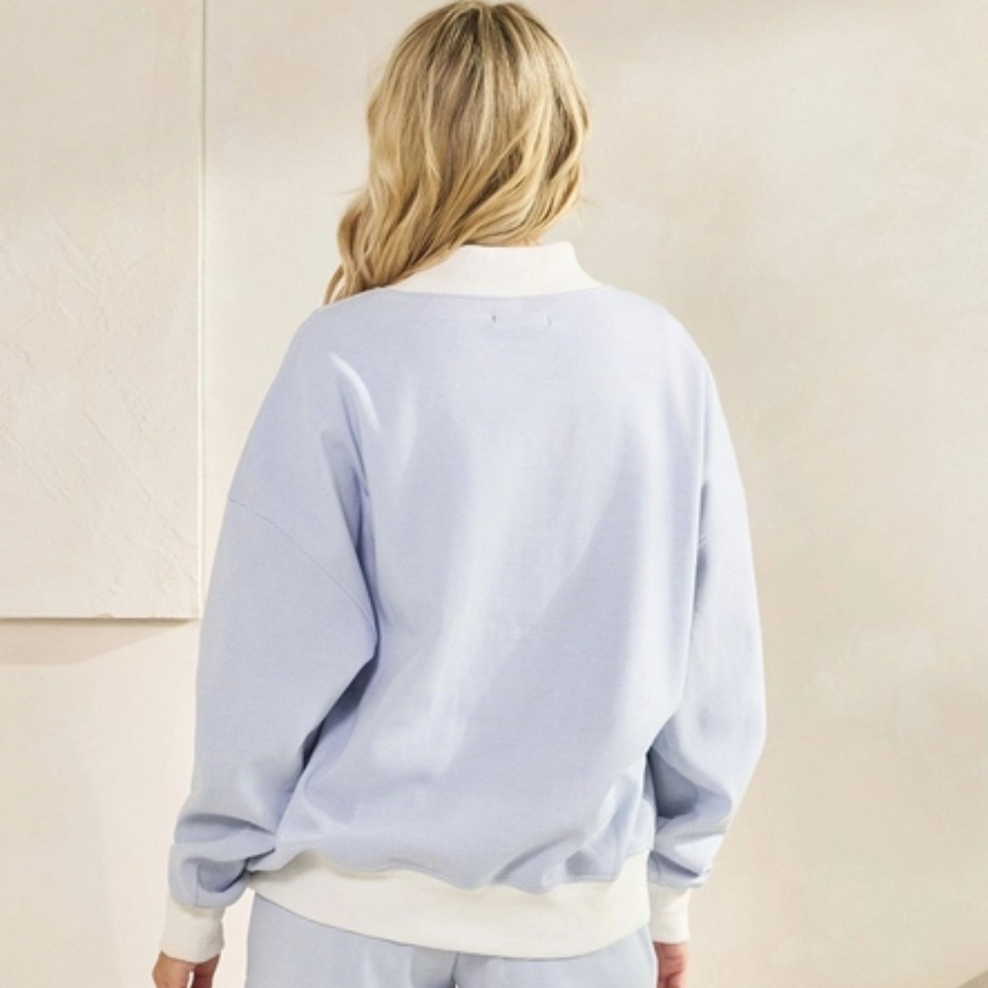 Person wearing a light blue sweatshirt with a plain background