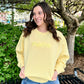 Woman wearing a yellow sweatshirt with 'mama' text outdoors.