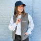 young woman wearing a lightweight grey fleece vest with custom text embroidered  on the left chest in white thread