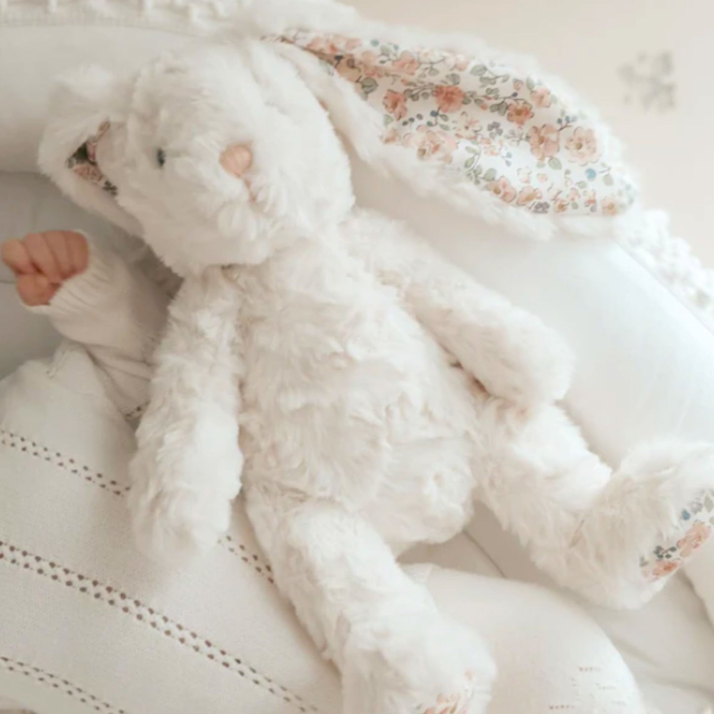 Fluffy white bunny toy with floral pattern on a soft white background