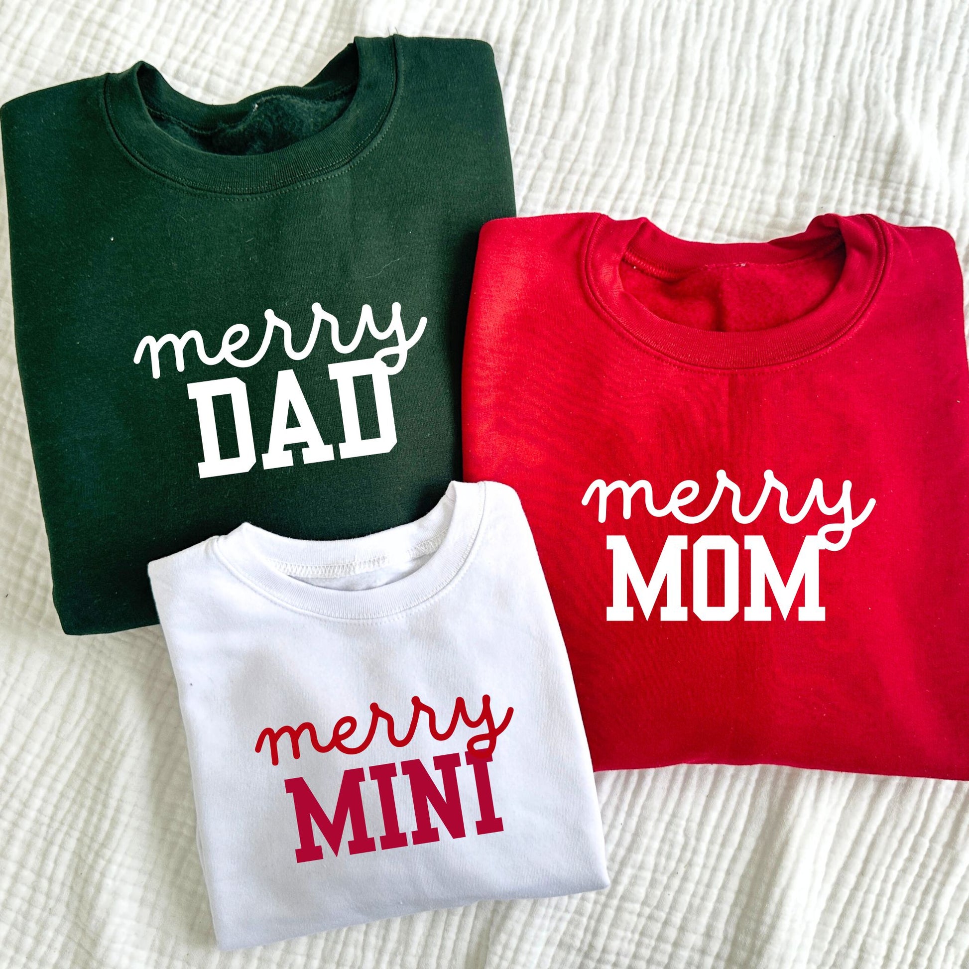 group of three coordinating family sweatshirts in forest green, red, and white with custom merry prints