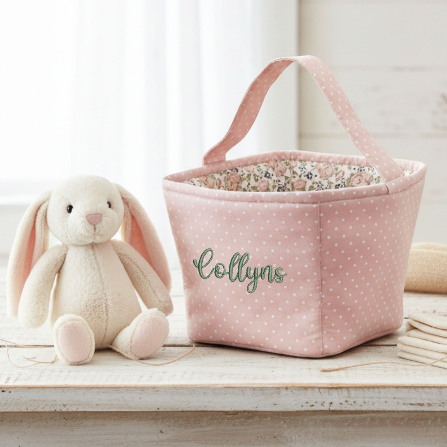 Pink polka dot storage basket with floral interior next to a plush bunny toy on a wooden surface.