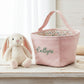 Pink polka dot storage basket with floral interior next to a plush bunny toy on a wooden surface.