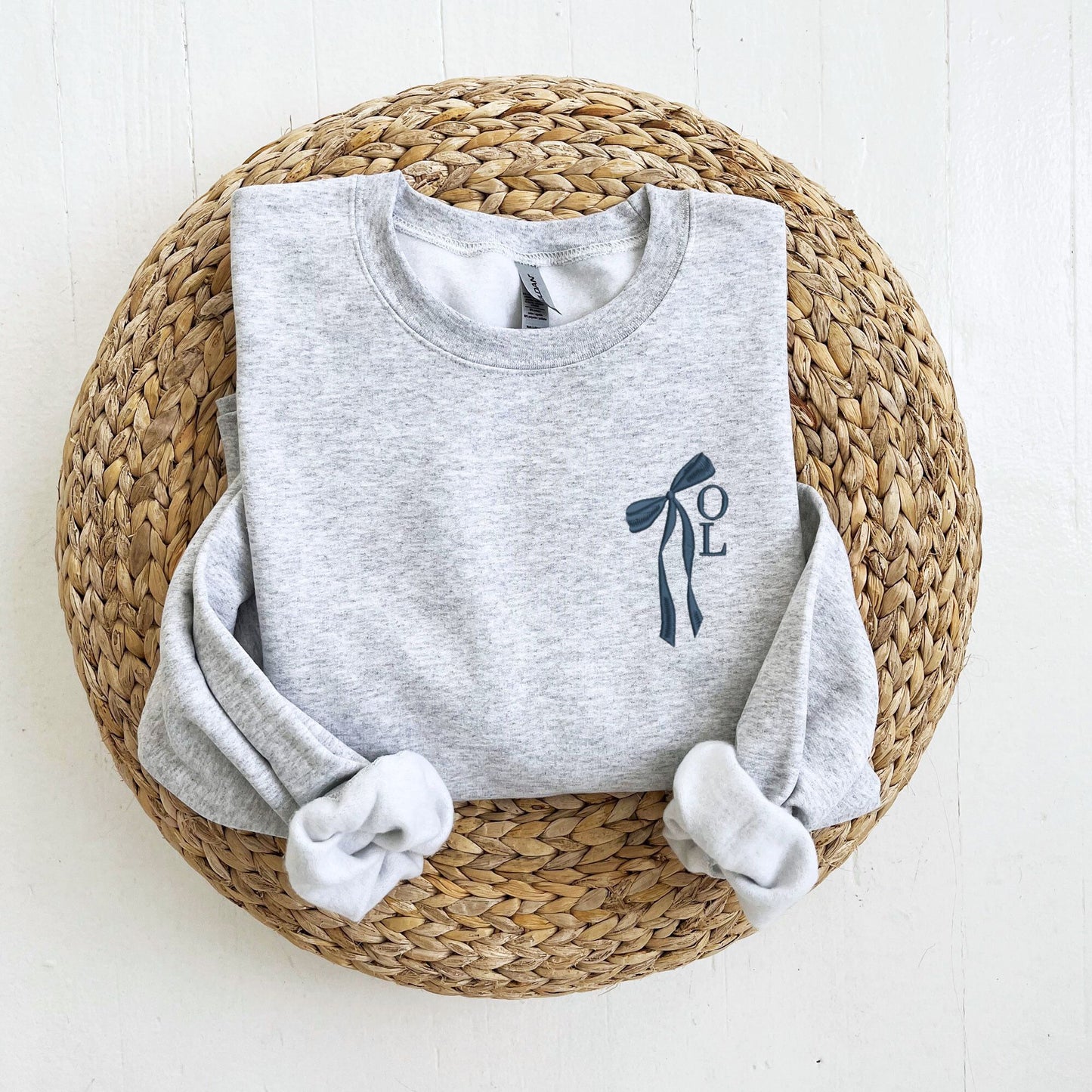 ash crewneck sweatshirt with custom ribbon bow and stacked initials embroidered on the left chest with navy thread