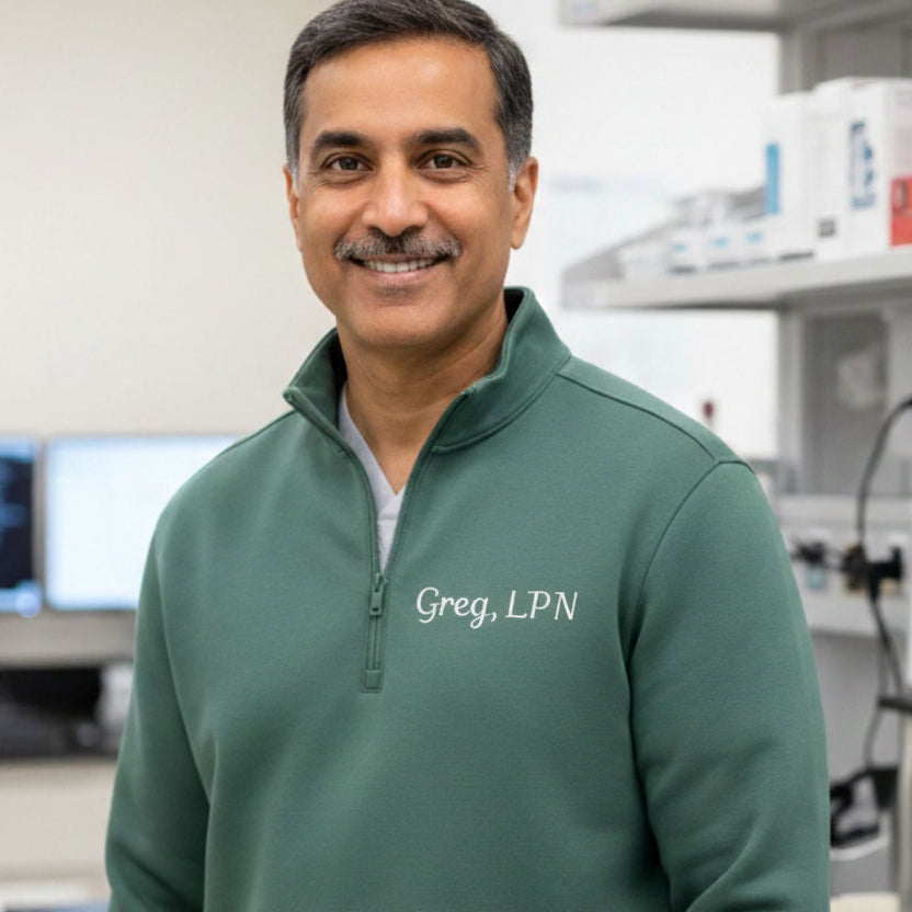 Man wearing a green pullover with 'Greg, LPN' in a laboratory setting