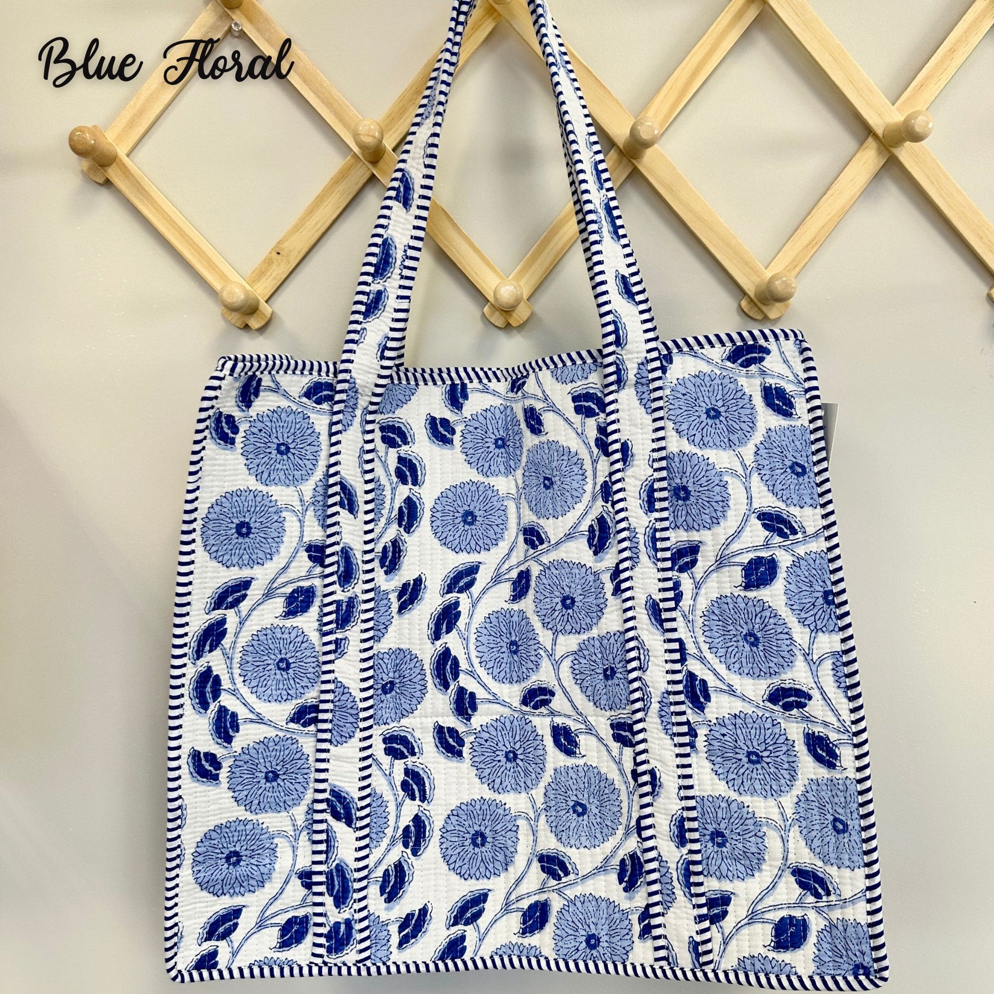 Two blue floral tote bags hanging on a wooden rack.