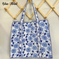 Two blue floral tote bags hanging on a wooden rack.