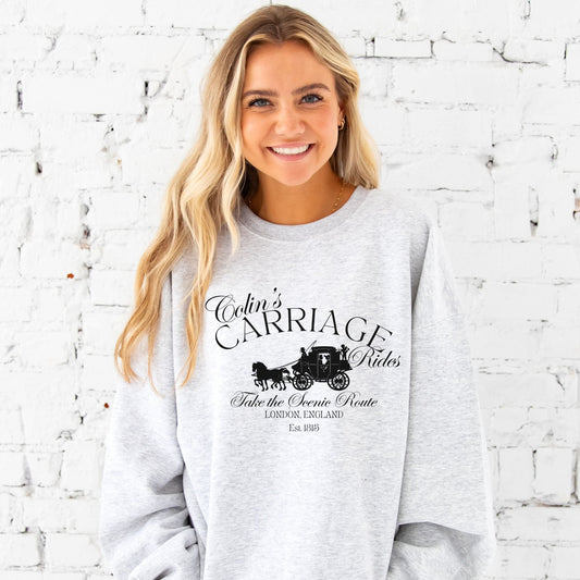 girl sitting in bed drinking coffee wearing an oversized ash crewneck sweatshirt with a mocha colin's carriage rides printed design