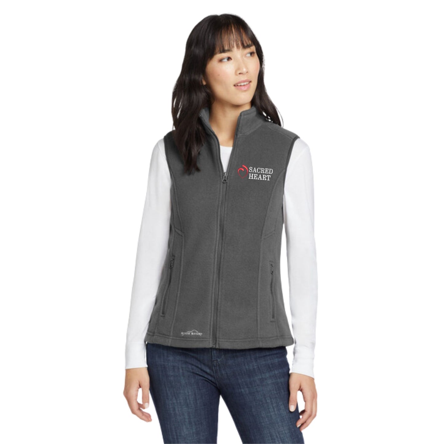 woman wearing a grey fleece eddie bauer vest with custom sacred heart logo embroidered design in red and white thread on the left chest