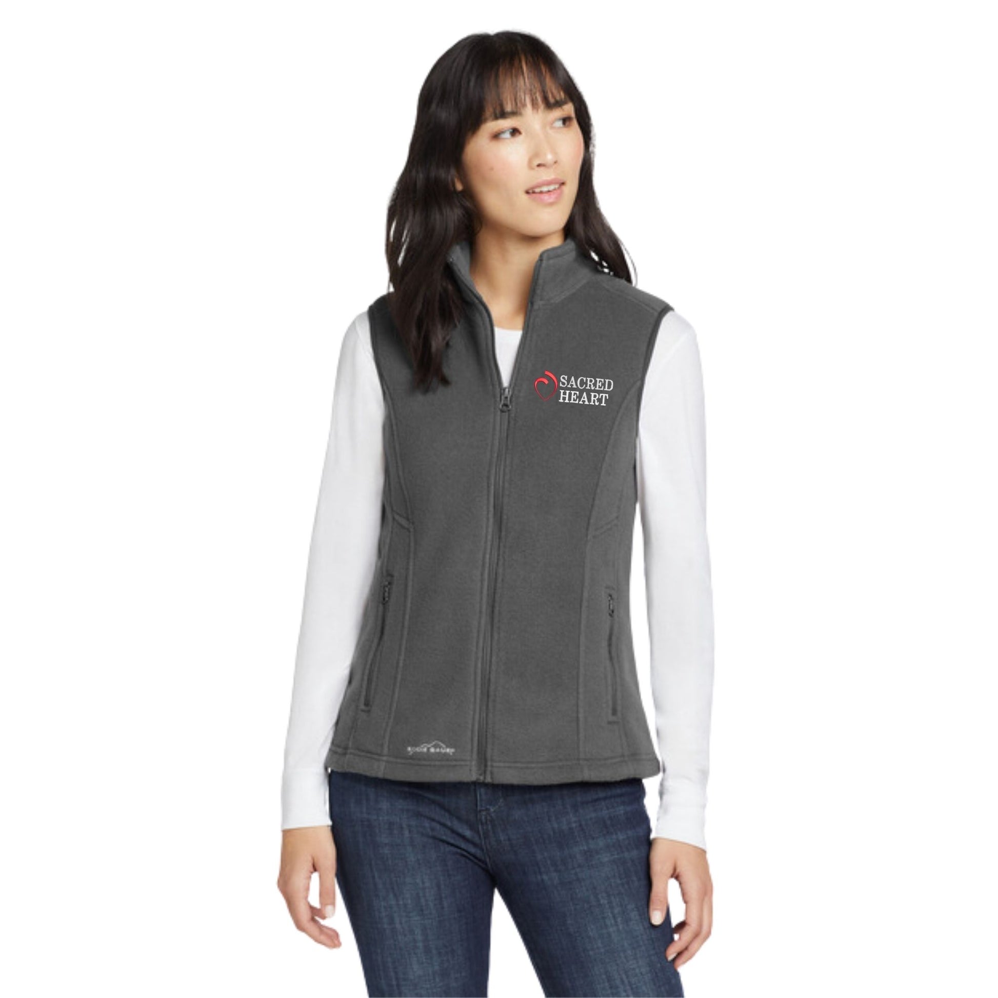 woman wearing a grey fleece eddie bauer vest with custom sacred heart logo embroidered design in red and white thread on the left chest