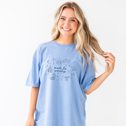 girl wearing a washed denim comfort colors t-shirt with custom made to worship printed design featuring cute Christian themed drawn icons