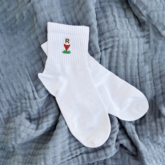 white crew socks with custom golf ball and tee embroidered icon with single letter monogram embroidered on top of the golf ball.