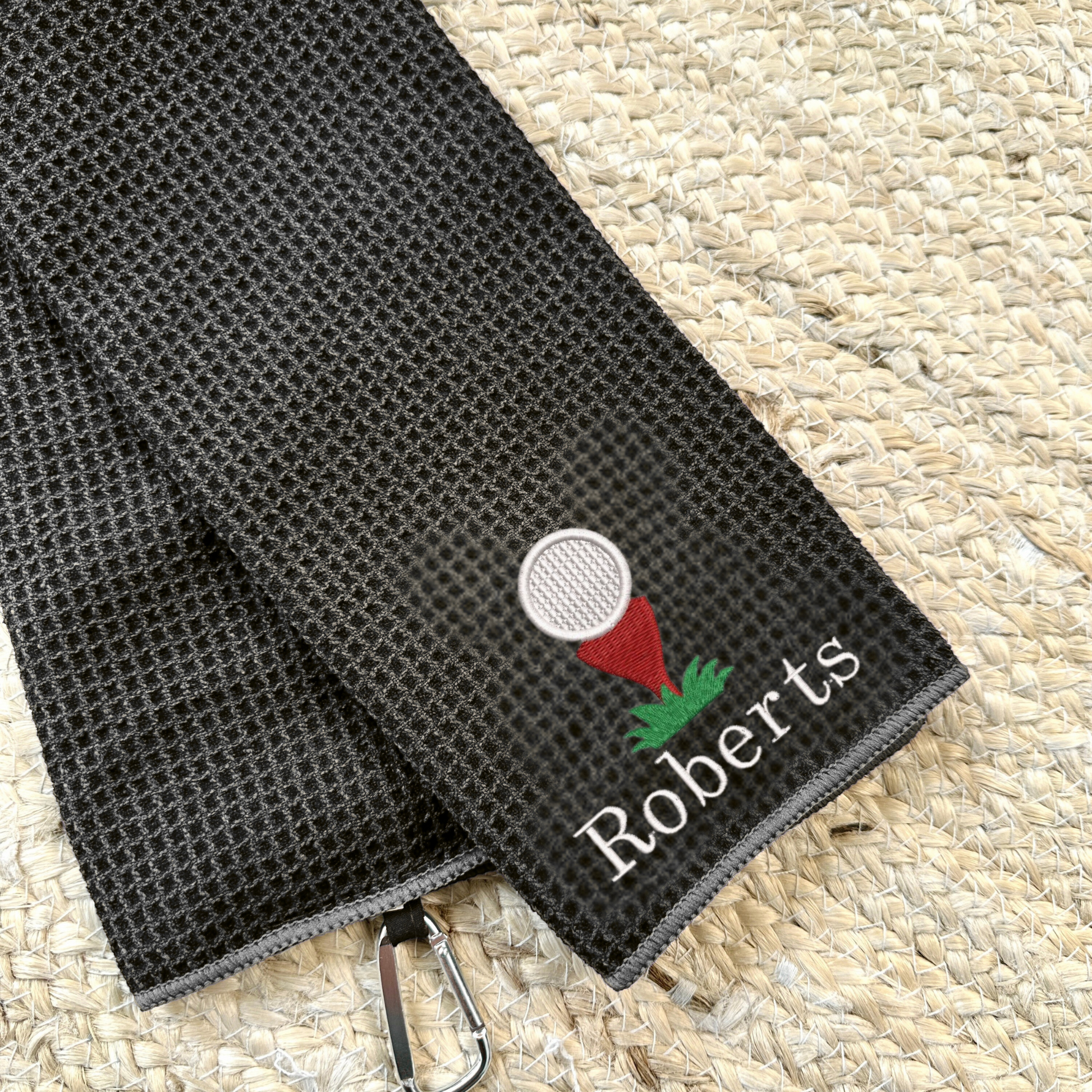 Deep Smoke tri-fold waffle microfiber golf towel with carabiner and custom golf ball/tee and Schoolbook font custom text in white thread embroidered design