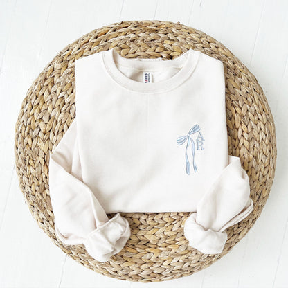 sweet cream crewneck sweatshirt with custom ribbon bow and stacked initials embroidered on the left chest with powder blue thread