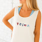Woman wearing an ivory tank top with embroidered designs on a white background
