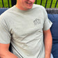 man wearing a bay comfort colors t-shirt with custom mountain icon and dad/custom year embroidered design on the left chest in grey thread