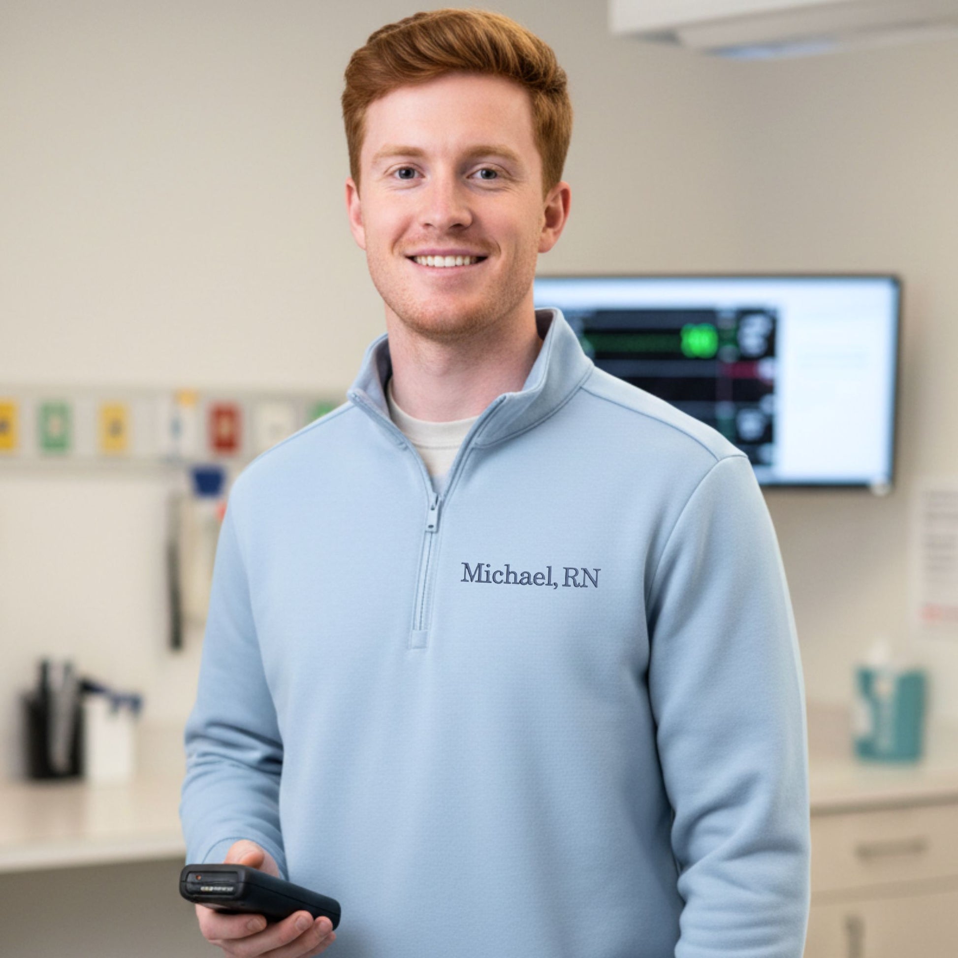 Man wearing a light blue sweater with 'Michael, RN' printed on it, standing in a medical setting.