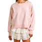 woman wearing a ruffle white skirt and a pink sweatshirt with floral sleeves 