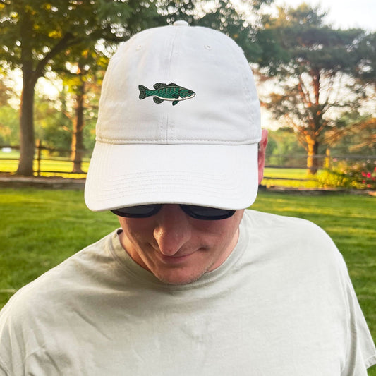 man standing outside wearing a stone baseball cap with custom embroidered bass fish icon on the front center in shades of green