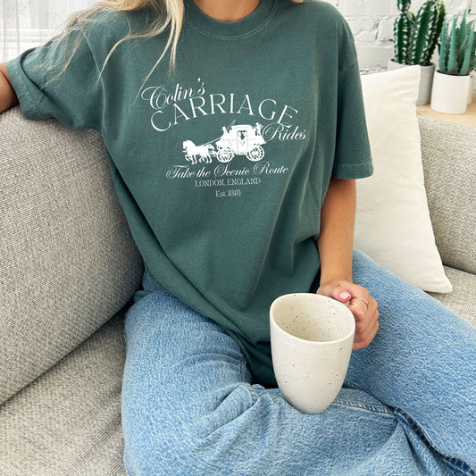 girl sitting on a couch drinking coffee wearing a blue spruce tee with a white colin's carriage rides printed design