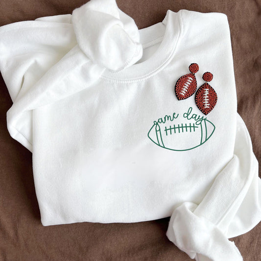 white crewneck sweatshirt with an outlined football game day embroidered design on the left chest in hunter green thread