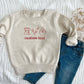 toddler heather oatmeal crewneck sweatshirt with embroidered baking icons and custom text in red thread