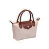 A small structured handbag with a light beige body and dark brown leather handles, trim, and front flap closure, shown on a plain white background.