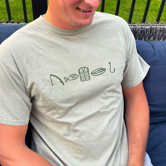man wearing a bay comfort colors t-shirt with custom fishing icons printed design across the chest. design featuring a fishing rod, fish, vest, boat, and hook in a darker green ink