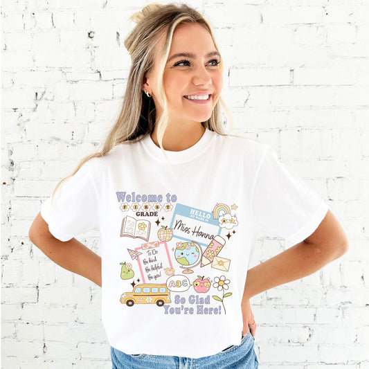 woman wearing a white comfort colors welcome to grade level and name t-shirt with cute school themed colorful icons