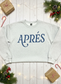 Gray sweatshirt with 'APRéS' text on a wooden surface with Christmas decorations.