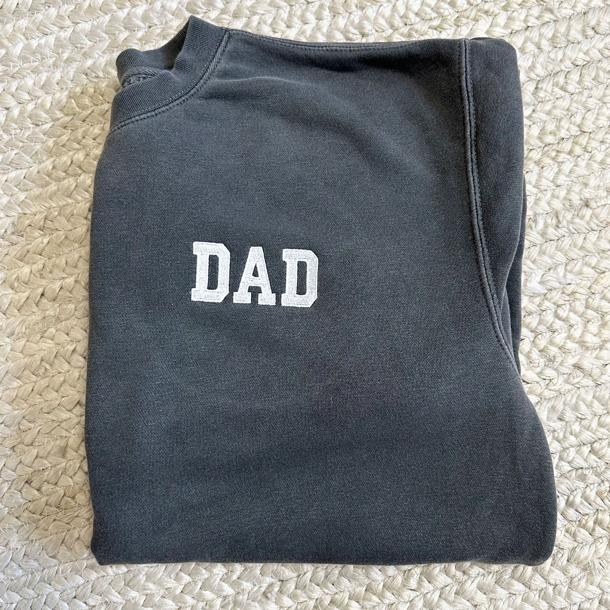 Black crewneck sweatshirt with varsity block letters DAD embroidered on the left chest.