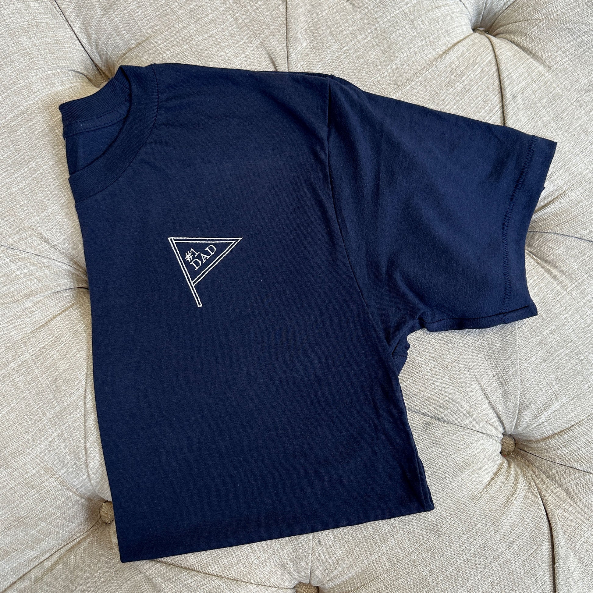 flat lay of a avy tee with #1 dad inside a mini pennant design
