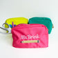 styled photo of a neon yellow, turquoise, and coral pink pencil bag pouches with emrboidered ms brink and pencil design on the coral pink bag. 