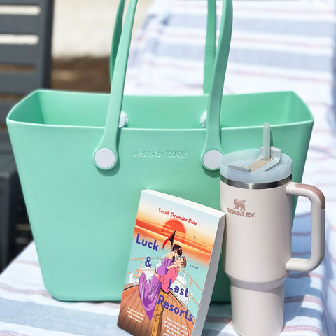 image of a mint green versa tote bag, a book, and a stanley water bottle