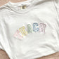 white comfort colors t-shirt with embroidered teach in pastel rainbow thread