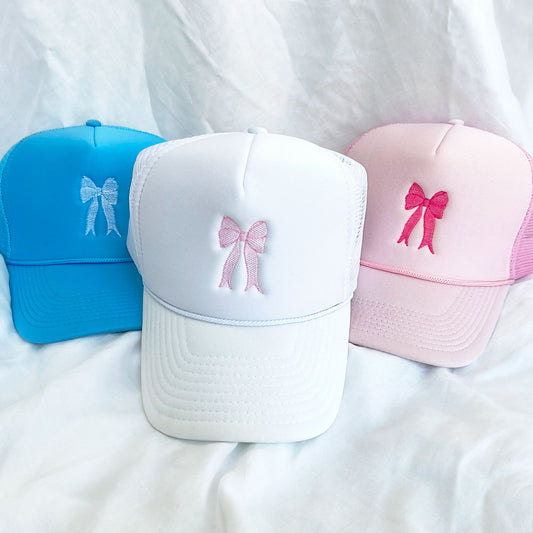 3 trucker hats in colors white pink and blue with embroidered bow design in white and pink threads 