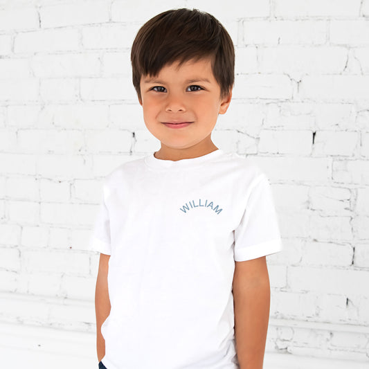 little boy wearing a white t-shirt with custom name arched embroidered design on the left chest