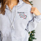 close up image of a woman's custom full zip jacket with pockets and personalized name, credentials, and christmas lights stethoscope design embroidered on the left chest