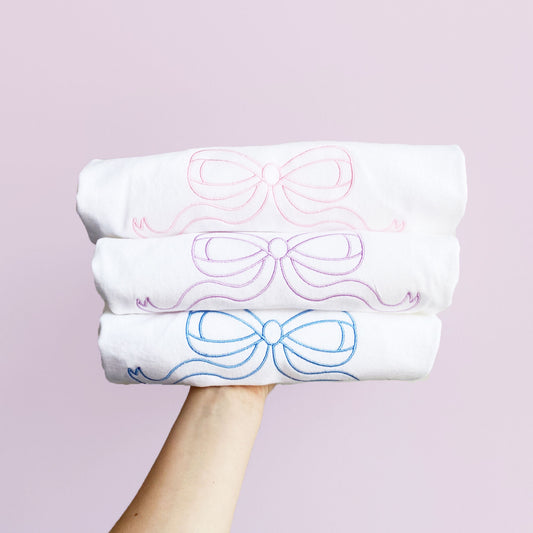 stack of white tees with embroidered outline bows