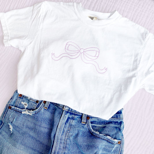 outfit layout featuring jeans and a white comfort colors tee with large outlined embroidered bow on the center