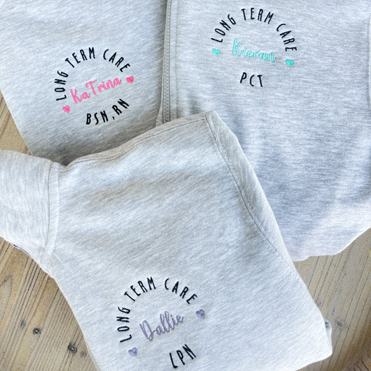 a group of collared quarter zips with pockets featuring a round custom nurse embroidered design on the left chest