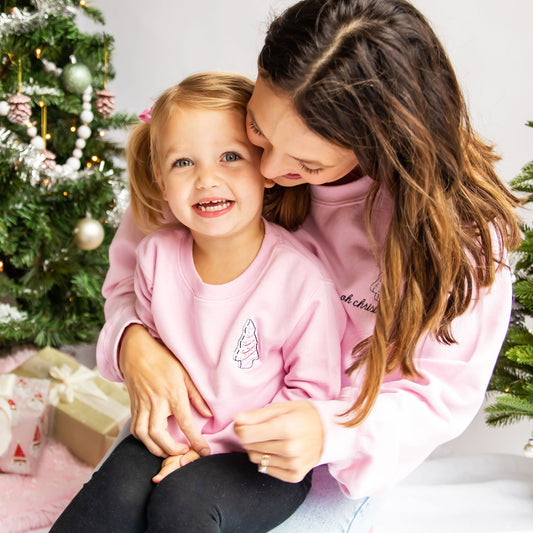 little girl and her mom wearing matching pink sweatshirts with a little debbie design on the left chest