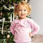 toddler standing in front of a decorated christmas tree wearing a light pink crewneck sweatshirt with a cute white, pink, and lilac embroidery design on the left chest