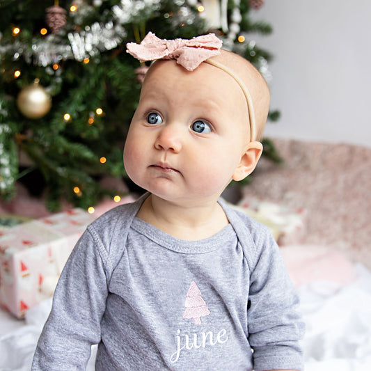 little girl  sitting by tree wearing custom christmas onesie