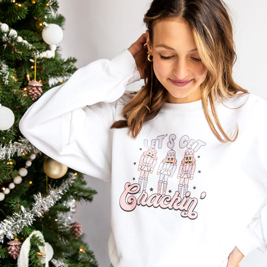 women wearing a white crewneck sweatshirt with a let's get cracking nutcracker printed design