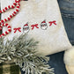 Gray sweatshirt with santa/bow embroidered designs paired with blue jeans
