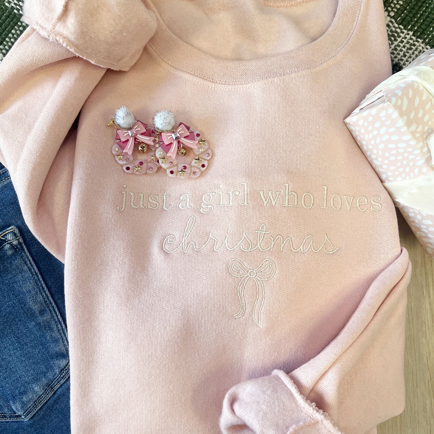 Pink sweater with Christmas-themed design and text 'just a girl who loves Christmas' on a neutral background.