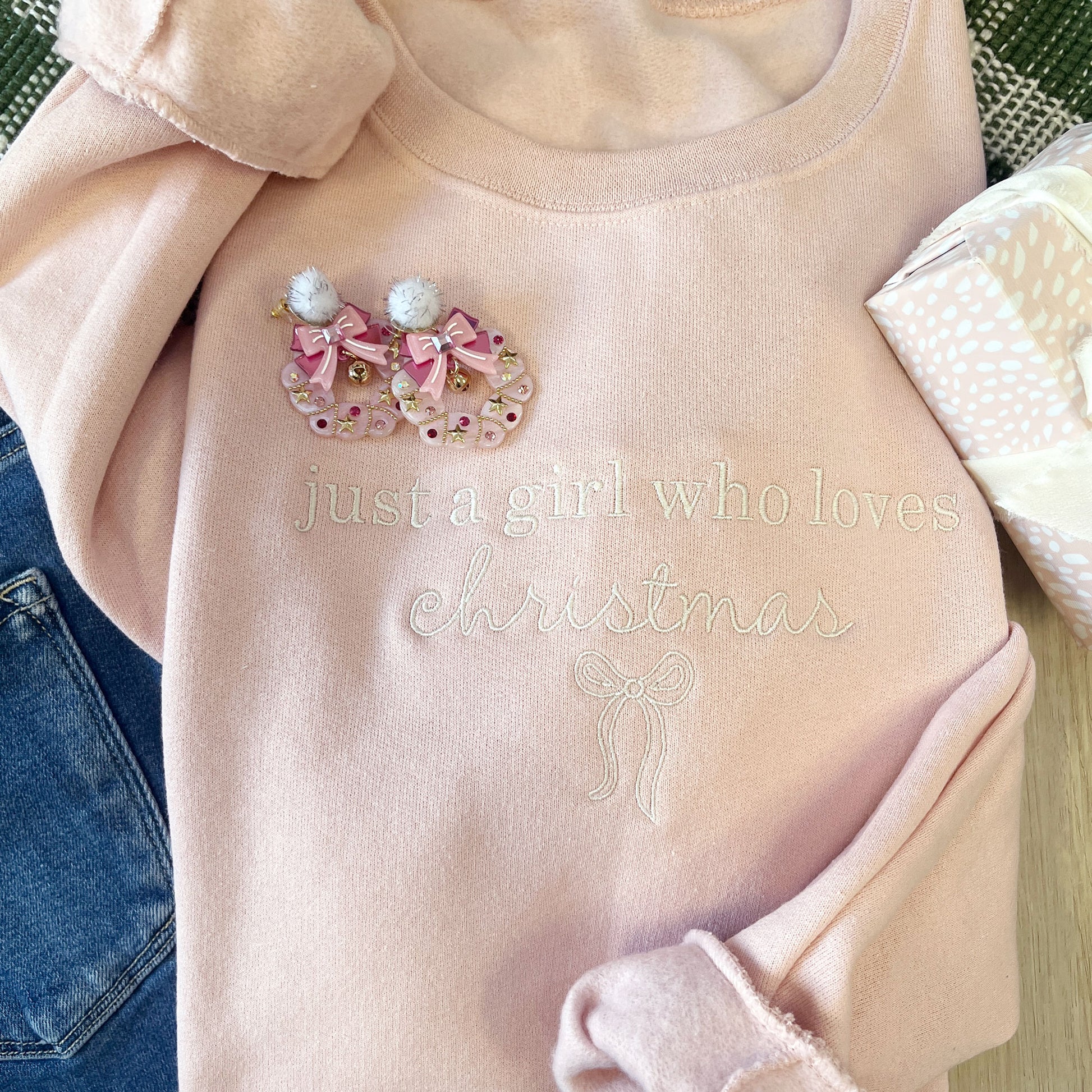 Pink sweater with Christmas-themed design and text 'just a girl who loves Christmas' on a neutral background.