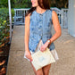 woman wearing sunglasses, denim vest, and skirt holding a light beige straw woven wristlet clutch with a custom two letter embroidered monogram in powder blue thread